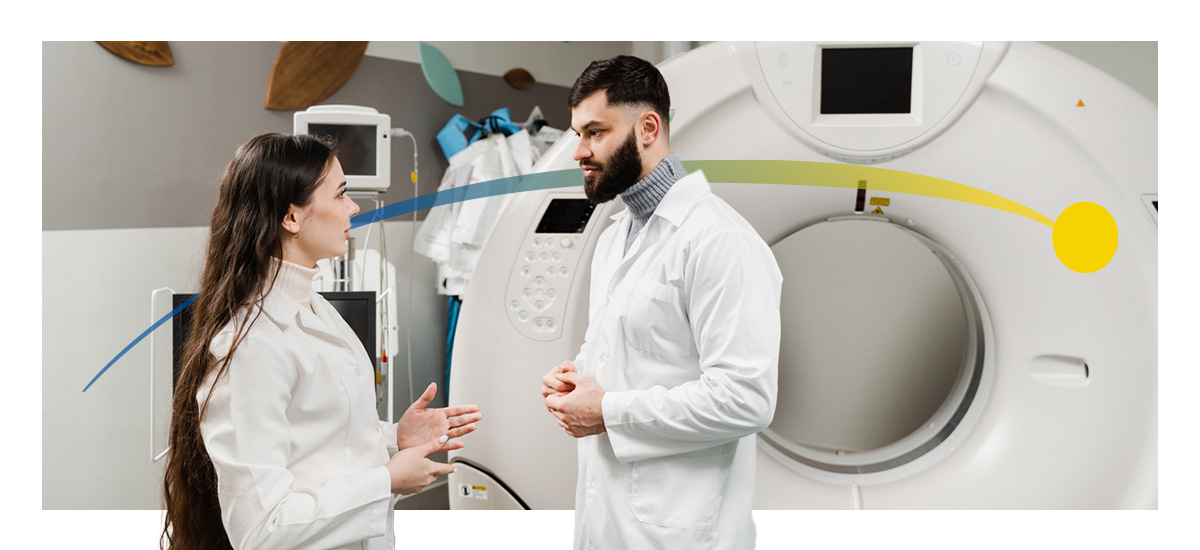 Two radiology doctors speak in front of an MRI machine